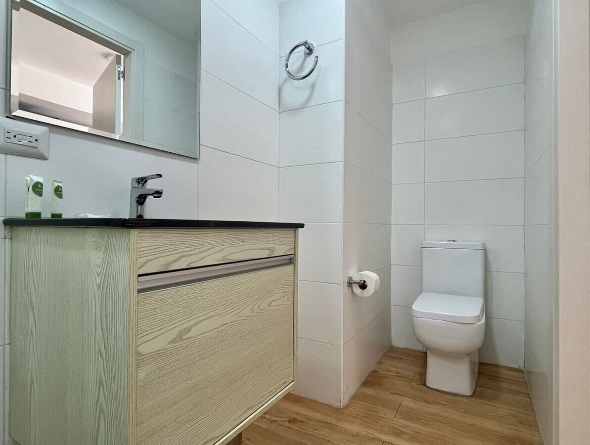 Une petite salle de bain comprenant des toilettes, un lavabo avec un miroir au-dessus et un meuble-lavabo en bois.