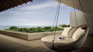 A hanging chair with cushions on a balcony overlooking a sea view.