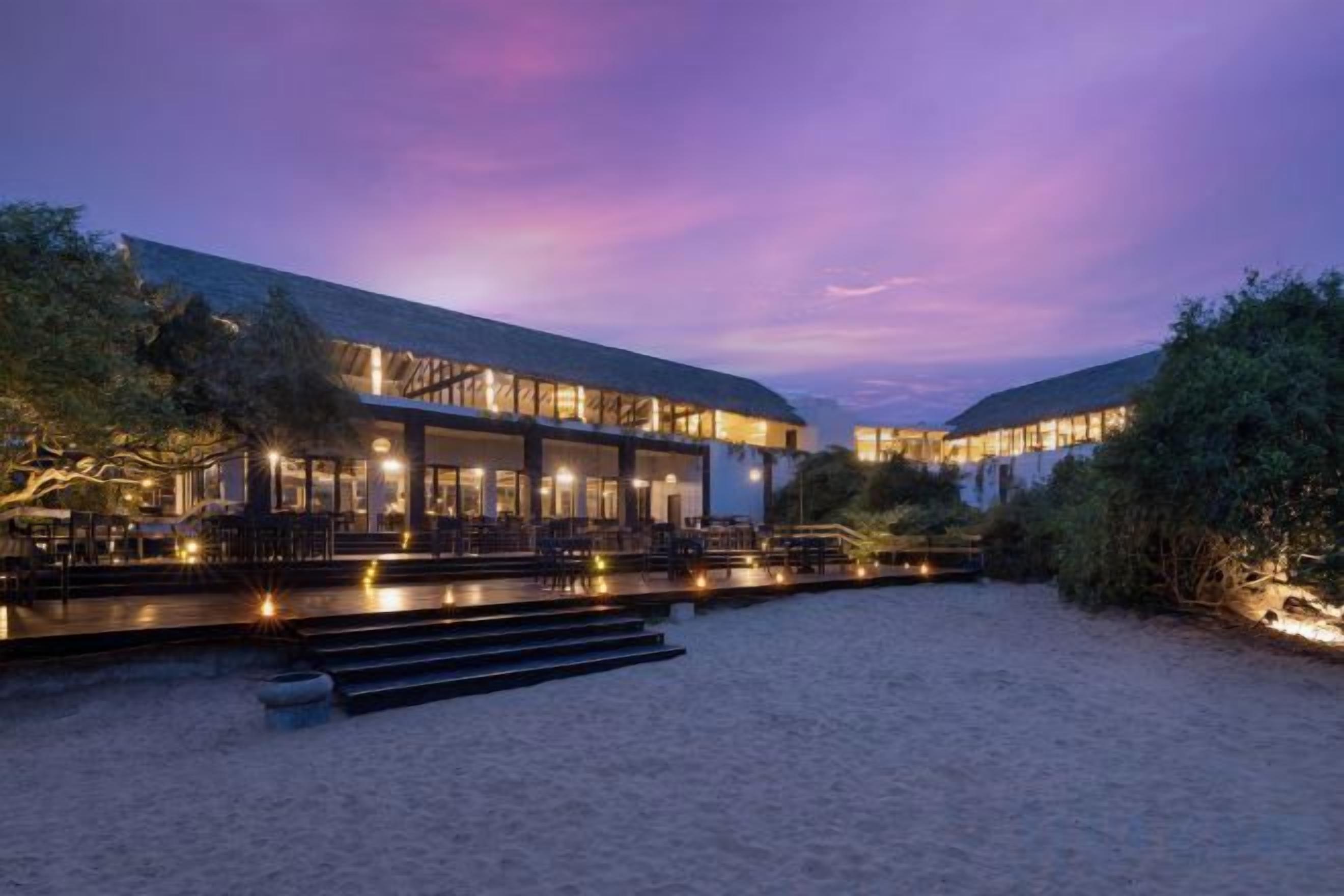 A beachfront hotel with a spacious outdoor area, a covered seating area, and a pool.