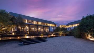 A beachfront hotel with a spacious outdoor area, a covered seating area, and a pool.
