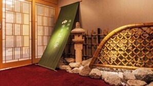 Ein traditioneller japanischer Raum mit Tatami-Böden, einer Shoji-Schiebetür, einem Bamboogitter-Bildschirm und einer grünen Hängerrolle.