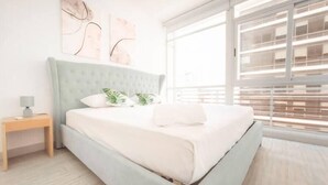 Un dormitorio moderno con cama, mesita de noche y una obra de arte en la pared.