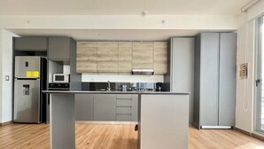 A modern kitchen with grey cabinets, a central island, and a stainless steel refrigerator.