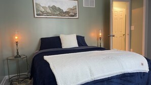 Una camera da letto con un letto, due lampade sui comodini, un quadro appeso al muro e una porta.