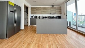 A modern kitchen with a central island, stainless steel appliances, and a view of the city through large windows.