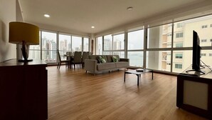 A spacious living room with a large window, a sofa, a coffee table, and a TV.