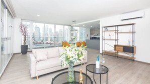 A modern living room with a sofa, a coffee table, and a vase of flowers.