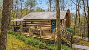 A rustic cabin with a wooden deck, a covered seating area, and a staircase leading to the entrance. - You need a Time Out on Your Next Getaway? (Sevierville)