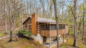 A cabin with a wooden exterior, a chimney, and a deck area. - You need a Time Out on Your Next Getaway? (Sevierville)