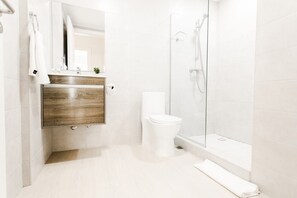 Ein modernes Badezimmer mit einem Holzkosmetikschrank, einer weißen Toilette und einer Duschkabine.