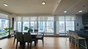 Un apartamento moderno con comedor, cocina y grandes ventanales que ofrecen vistas a la ciudad.