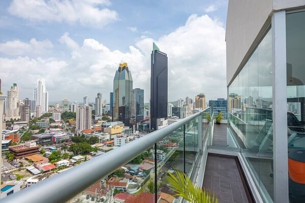 A high-rise building with a glass balcony overlooking a cityscape.