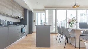 A modern kitchen with grey cabinets, a central island, and a dining area with grey chairs.