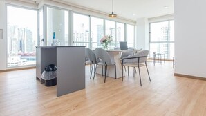 A modern kitchen with a dining area, large windows, and a city view.