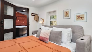A bedroom with a bed, a wooden door, a window, and two framed pictures on the wall. - Bungalow w/ Relaxing Private Hot Tub, Scenic Mountain Views (Cascade-Chipita Park)