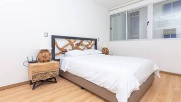 A bedroom with a bed, a nightstand, a decorative wall piece, and a window.