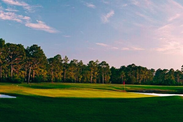 A golf course with a red flag on the green, surrounded by trees and a clear sky. - Shadow Lakes Retreat ~Golfing, Beaches, 10 Min to OKI, Southport Ferry (Southport)