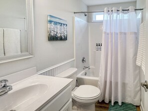 A bathroom with a white sink, toilet, and shower curtain. - Shadow Lakes Retreat ~Golfing, Beaches, 10 Min to OKI, Southport  Ferry (Southport)