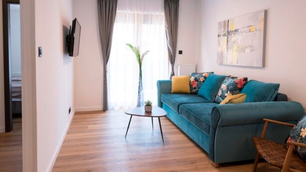 A modern living room with a teal sofa, a small round table, and a wooden chair. - Apartment Martinus-r (Sveti Martin na Muri)