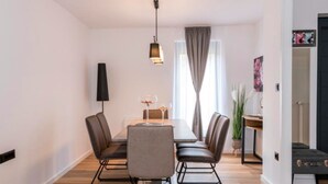 A modern dining area with a wooden table, leather chairs, and a pendant light. - Apartment Martinus-r (Sveti Martin na Muri)