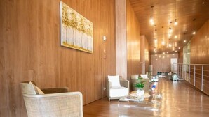 A spacious lobby with wooden walls, a large painting, and a seating area with a sofa and armchairs.