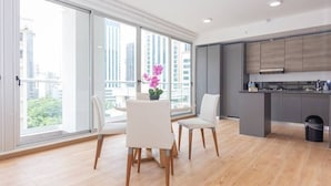 A modern kitchen with grey cabinets and a black trash bin. There are two white chairs and a small table with a vase of flowers. - Luxury 1 bedroom apt free parking and balcony (Panamá)