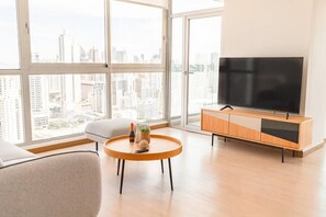 Una sala de estar moderna con un televisor grande, una mesa de centro redonda de madera y un sofá.