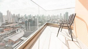 Ein Balkon in einem Hochhaus mit Blick auf die Stadt, einem Stuhl und einem Fliesenboden.