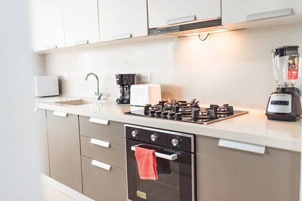 Una cocina moderna con horno empotrado, cafetera y licuadora sobre la encimera.