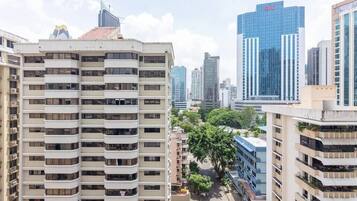A high-rise building with multiple balconies, surrounded by other tall buildings and trees.
