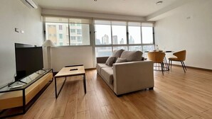 A modern living room with a sofa, TV, and dining area.