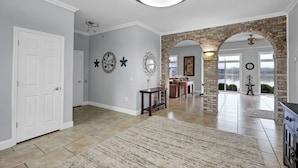 A spacious living area with a large rug, a fireplace, and a view of a lake through an archway. - Beautiful views and sunrises overlooking the water. Spacious home with elevator. (Jeffersonville)