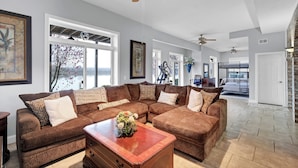 A spacious living room with a sectional sofa, a coffee table with a floral arrangement, and ceiling fans. - Beautiful views and sunrises overlooking the water. Spacious home with elevator. (Jeffersonville)