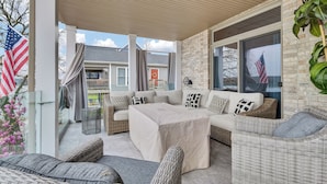 A covered outdoor seating area with wicker furniture, American flags, and a view of neighboring houses. - Beautiful views and sunrises overlooking the water. Spacious home with elevator. (Jeffersonville)
