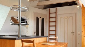 A compact kitchen with a wooden table and chairs, a built-in stove, and a hanging light fixture.