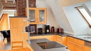 A modern kitchen with wooden cabinets, a black countertop, and a built-in stove.