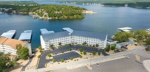 A hotel with a central courtyard, parking lot, and a view of a lake. - Next door to Dog Days Grill! Waterfront with amazing views! JACUZZI TUB (Osage Beach)