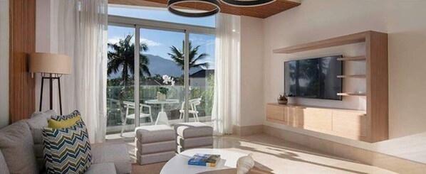 Una sala de estar moderna con un televisor grande, asientos cómodos y vistas a palmeras.