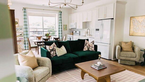 Un salon avec un canapé vert, une table basse en bois et un fauteuil beige.
