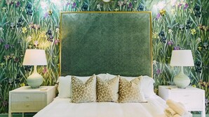 Une chambre à coucher avec une tête de lit à motifs, deux tables de chevet avec des lampes et un lit agrémenté d’oreillers à motifs.