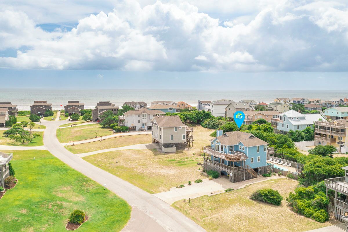 A coastal residential area with houses, a road, and a view of the ocean.