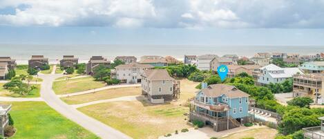A coastal residential area with houses, a road, and a view of the ocean.