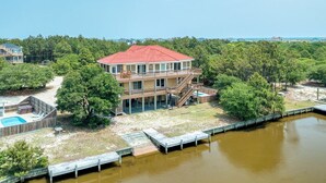 Ein zweistöckiges Haus mit rotem Dach, einem Pool und einem Steg, der sich über das Wasser erstreckt.