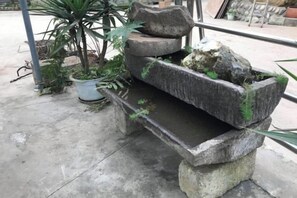 A stone water feature with a small basin and a potted plant nearby. - Mount Emei Feng Lin Yue Hotel (Emeishan City)