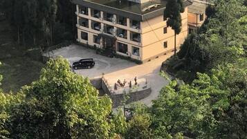 A multi-story building with a flat roof, surrounded by dense greenery.
