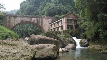A stone bridge, a waterfall, and a building with a red roof.