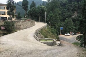 Uma estrada sinuosa com um muro de pedra de um lado e um edifício com uma placa do outro.