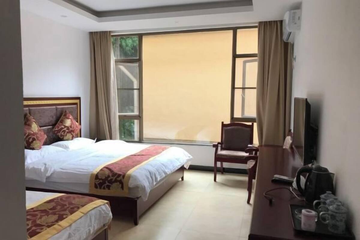 A hotel room with a bed, a chair, a desk, a television, and a window.