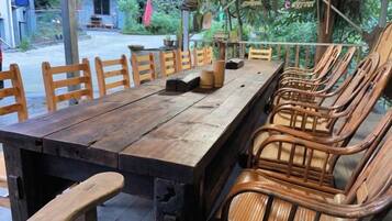 A long wooden table with chairs, a small table lamp, and a wooden block.