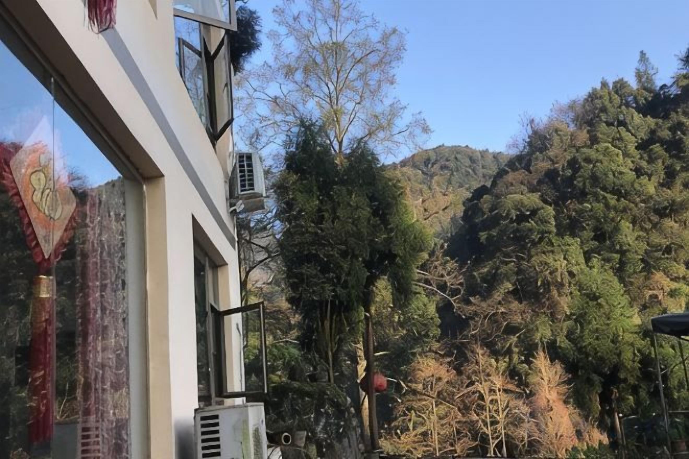 A building with air conditioning units and a view of a forested hillside.